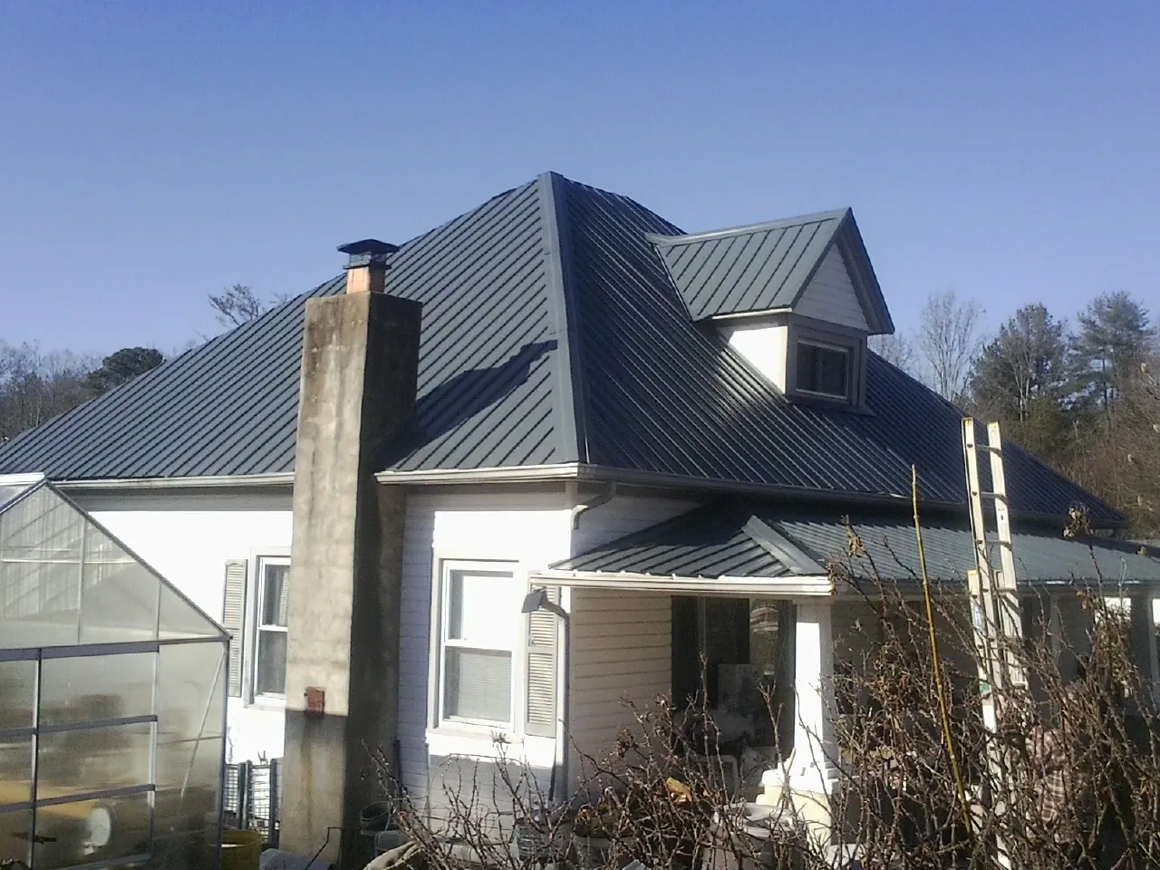 Dark blue standing seam metal roof on a white farmhouse with dormer — Slate & Tile Roof Repair by Roofing Brothers in Duxbury