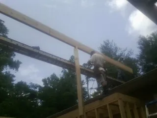 Carpenter setting a ridge beam over a new addition frame — Ice Dam Removal by Roofing Brothers in Duxbury