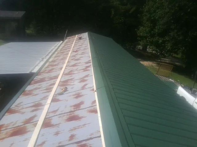 Old rusted panels beside newly installed green metal roofing — Wind Damage Roof Repair by Roofing Brothers in Duxbury