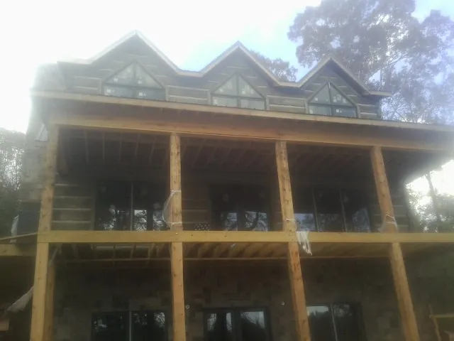 Dormers and porch framing on a large log home under construction — Roof Coating work by our crew in Duxbury