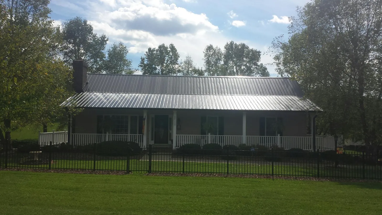 Gray metal roof on a brick ranch with a full width front porch — Gutter Guard Installation work by our crew in Duxbury